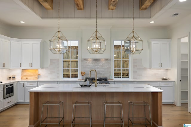 kitchen with a center island with sink, a breakfast bar, and white cabinets