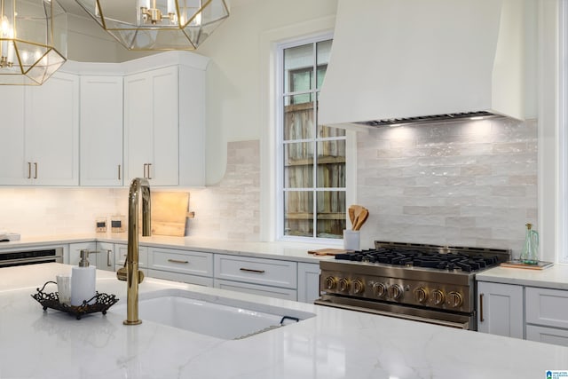 kitchen with custom exhaust hood, decorative backsplash, stainless steel appliances, and hanging light fixtures