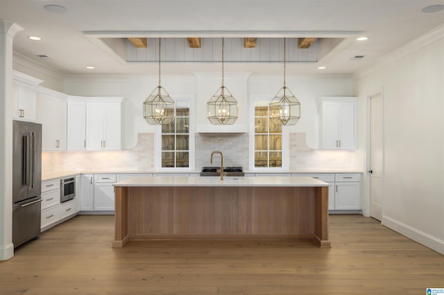 kitchen featuring a kitchen island with sink, white cabinets, decorative backsplash, light hardwood / wood-style floors, and stainless steel appliances