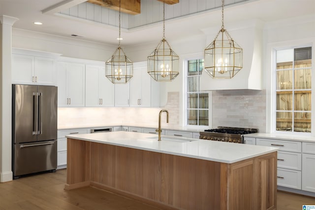 kitchen with appliances with stainless steel finishes, decorative light fixtures, white cabinetry, and an island with sink