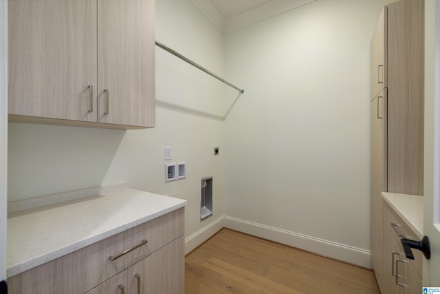 clothes washing area with washer hookup, electric dryer hookup, cabinets, and light hardwood / wood-style flooring