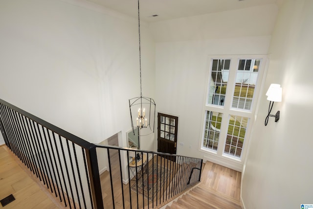 stairway with hardwood / wood-style flooring, a healthy amount of sunlight, and a chandelier