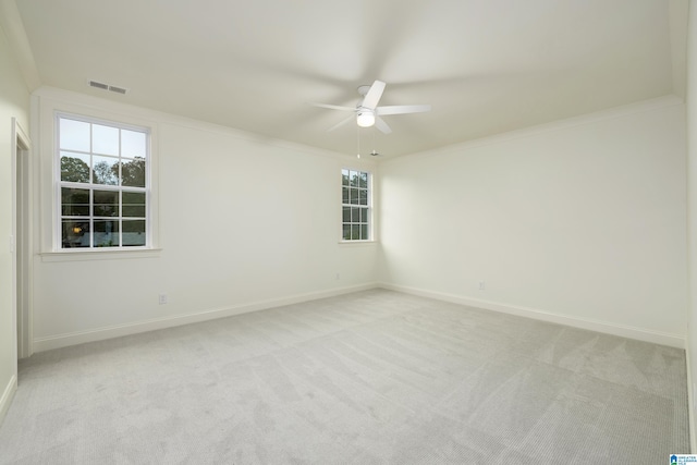 spare room with ceiling fan, ornamental molding, and light carpet