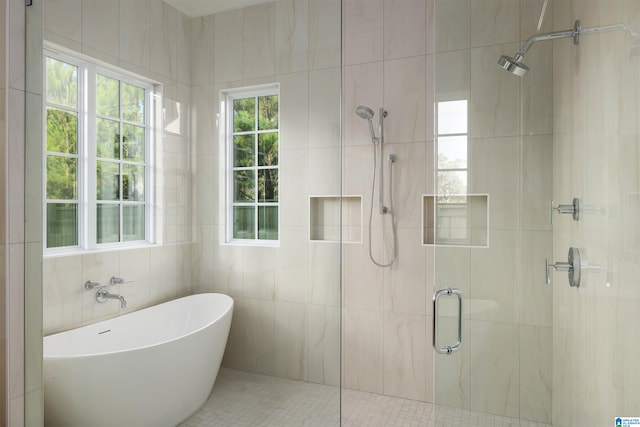 bathroom with plus walk in shower, tile patterned flooring, and tile walls