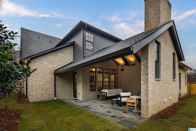 back of house with an outdoor living space, ceiling fan, a patio area, and a lawn