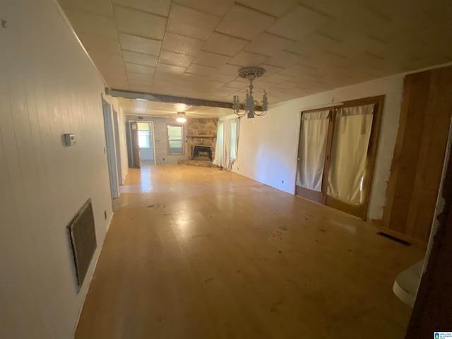 spare room featuring a chandelier, hardwood / wood-style flooring, and a fireplace