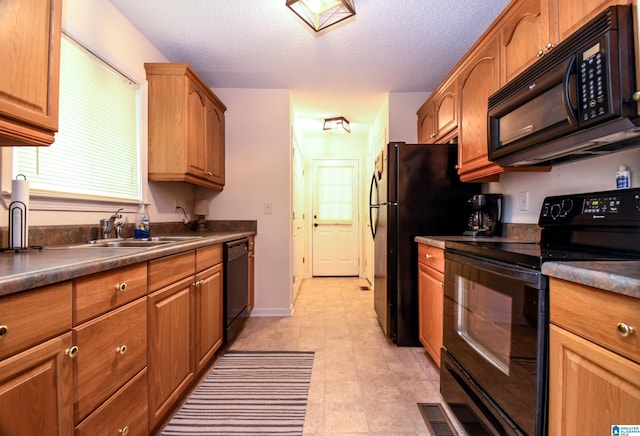 kitchen featuring a textured ceiling, black appliances, and light tile floors