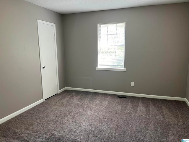 carpeted empty room with a textured ceiling