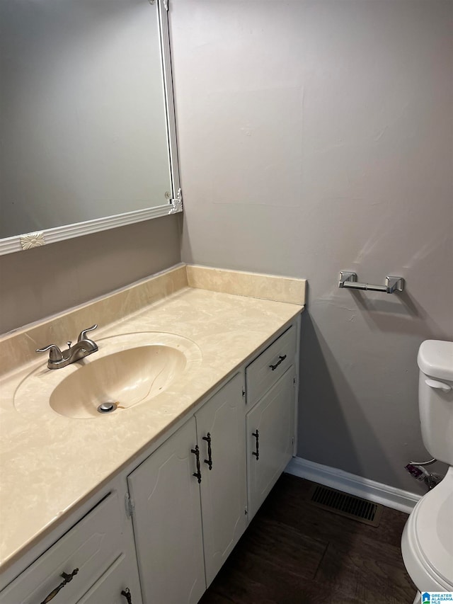 bathroom with wood-type flooring, large vanity, and toilet