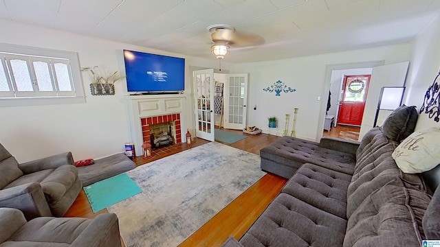 living room with dark hardwood / wood-style flooring, ceiling fan, and a brick fireplace