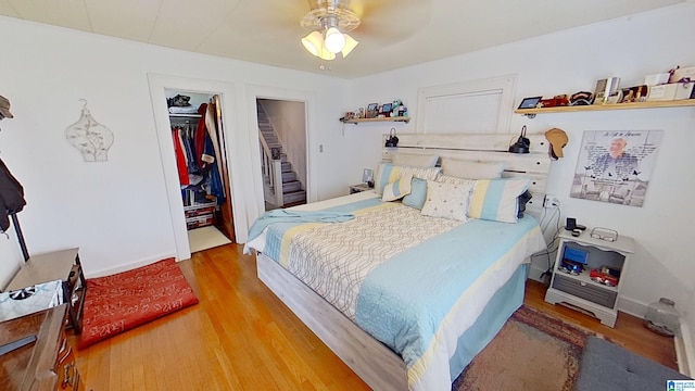 bedroom with a closet, light hardwood / wood-style floors, ceiling fan, and a walk in closet