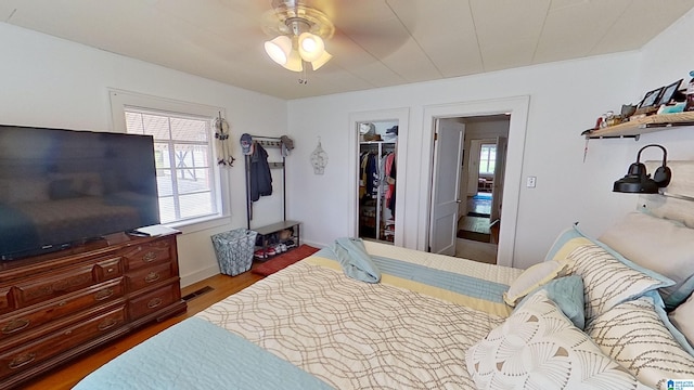 bedroom featuring a closet, multiple windows, ceiling fan, and dark hardwood / wood-style floors