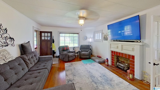 living room featuring dark hardwood / wood-style floors, ceiling fan, and a brick fireplace