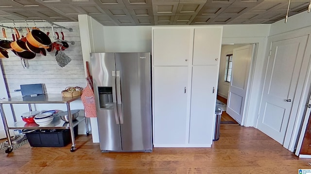 kitchen featuring hardwood / wood-style floors, stainless steel fridge, and white cabinetry