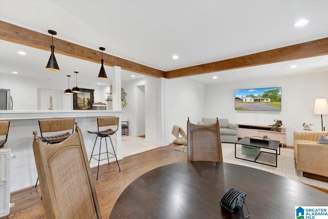 dining room with beamed ceiling and light hardwood / wood-style floors