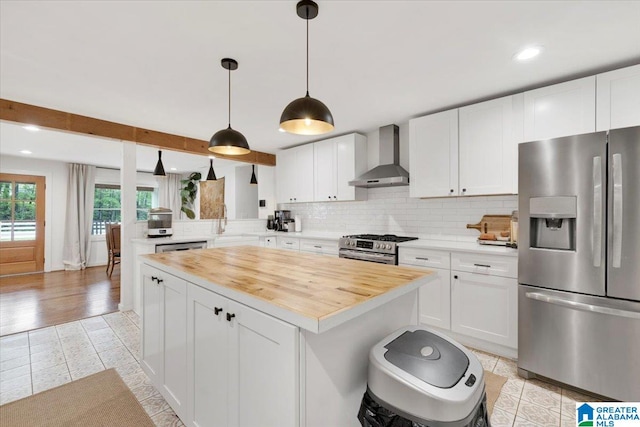 kitchen featuring white cabinets, wall chimney exhaust hood, and stainless steel appliances