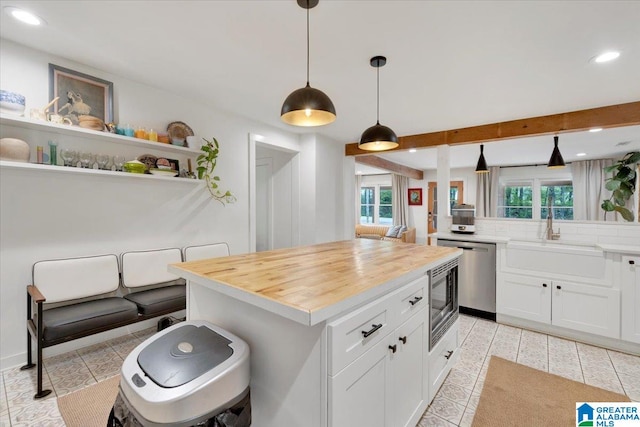 kitchen featuring white cabinetry, sink, pendant lighting, decorative backsplash, and a kitchen island