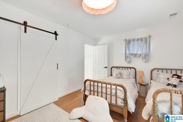 bedroom featuring a barn door and light hardwood / wood-style floors