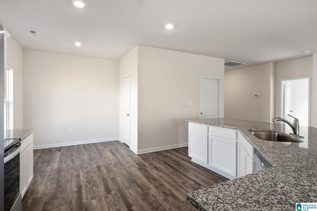 kitchen with appliances with stainless steel finishes, sink, white cabinetry, dark hardwood / wood-style floors, and dark stone countertops