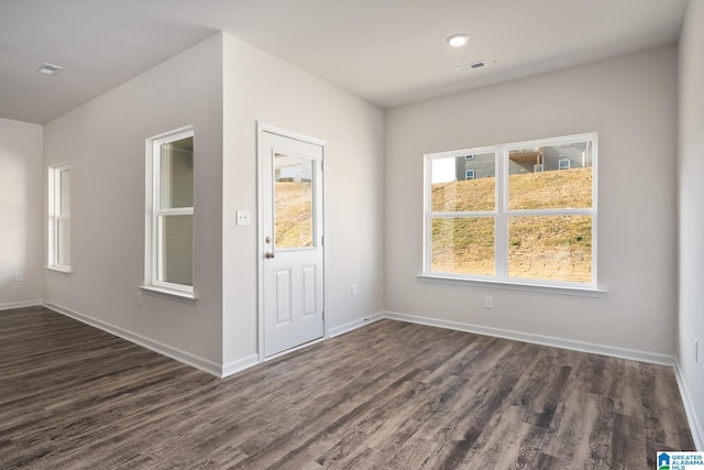 unfurnished room featuring plenty of natural light and dark hardwood / wood-style flooring