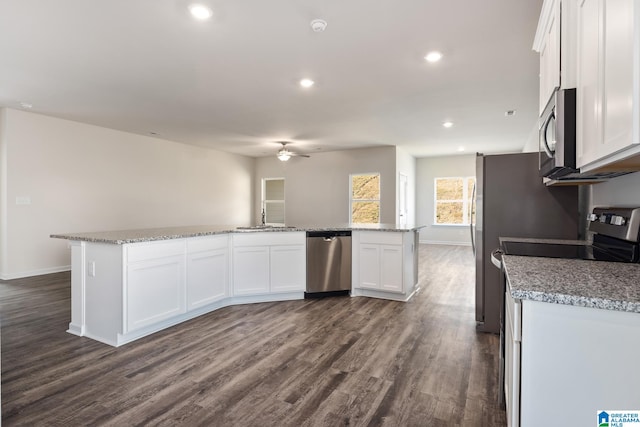 kitchen with appliances with stainless steel finishes, dark hardwood / wood-style floors, a kitchen island, and white cabinetry