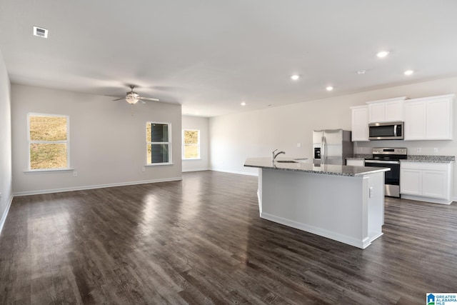 kitchen with dark wood-type flooring, white cabinetry, stainless steel appliances, sink, and an island with sink