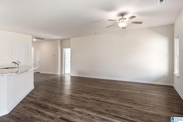 unfurnished living room featuring ceiling fan, sink, and dark hardwood / wood-style flooring