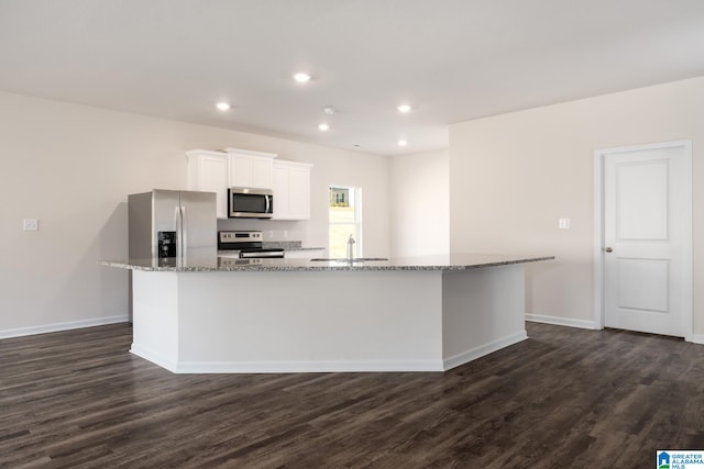 kitchen with a kitchen island with sink, dark wood-type flooring, stainless steel appliances, and white cabinetry