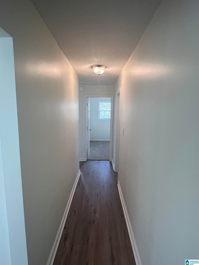 hall featuring dark wood-type flooring and a textured ceiling