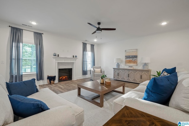 living room featuring ornamental molding, light hardwood / wood-style floors, and ceiling fan