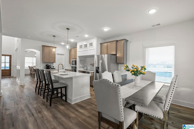 kitchen featuring plenty of natural light, a center island with sink, dark wood-type flooring, a kitchen breakfast bar, and pendant lighting