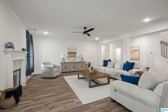 living room featuring crown molding, dark wood-type flooring, ceiling fan, and a tile fireplace