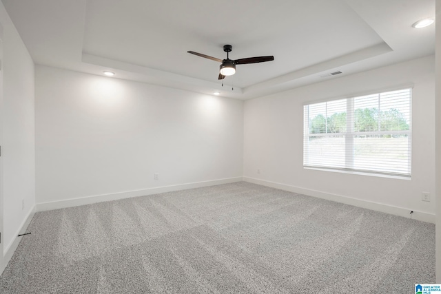 carpeted spare room featuring ceiling fan and a tray ceiling