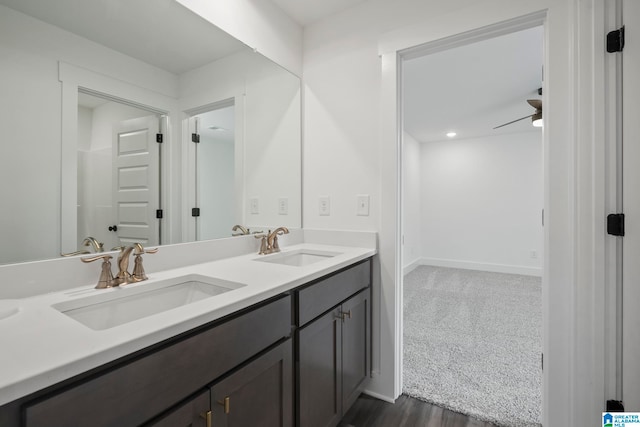 bathroom with ceiling fan, vanity with extensive cabinet space, hardwood / wood-style flooring, and dual sinks