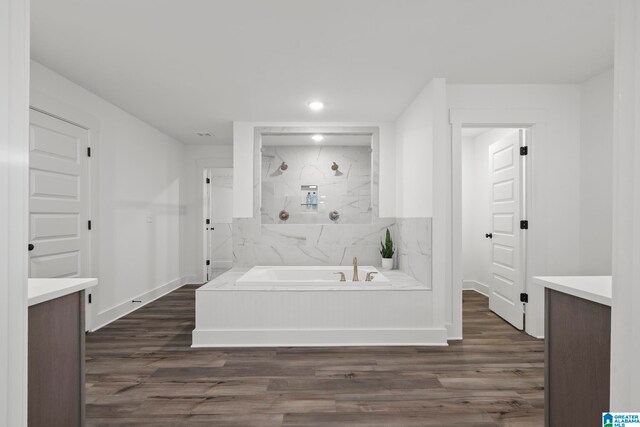 bathroom featuring wood-type flooring, vanity, and plus walk in shower