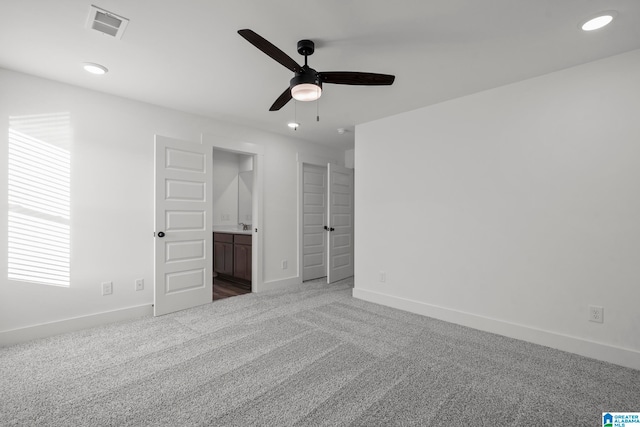 unfurnished bedroom with ceiling fan, ensuite bathroom, and carpet floors