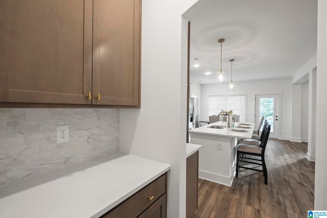 kitchen featuring backsplash, a breakfast bar area, dark wood-type flooring, sink, and pendant lighting