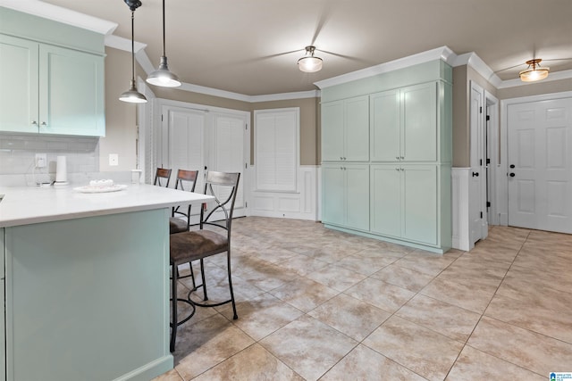 kitchen with a breakfast bar area, tasteful backsplash, light tile floors, and ornamental molding