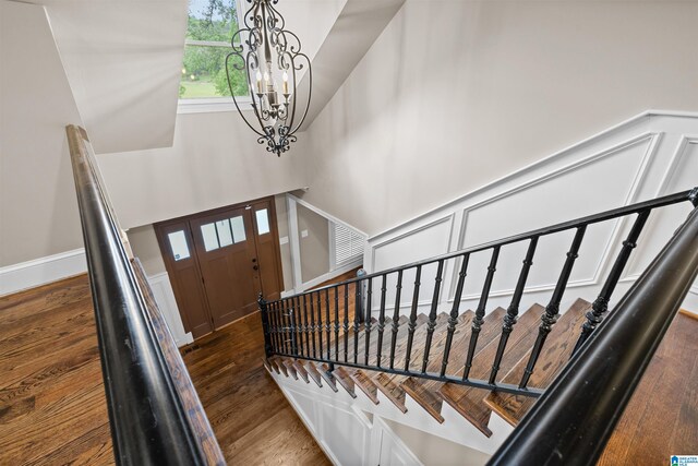 foyer entrance featuring a notable chandelier, a towering ceiling, and dark wood-type flooring