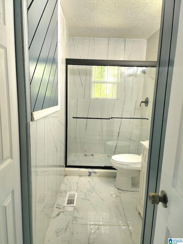 bathroom featuring vanity, a shower with shower door, tile flooring, toilet, and a textured ceiling