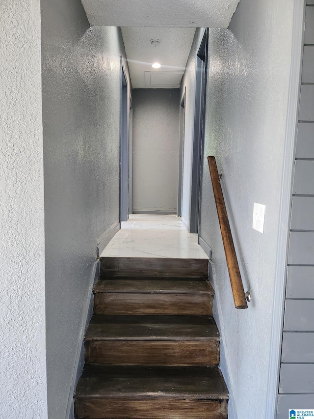 staircase featuring a textured ceiling