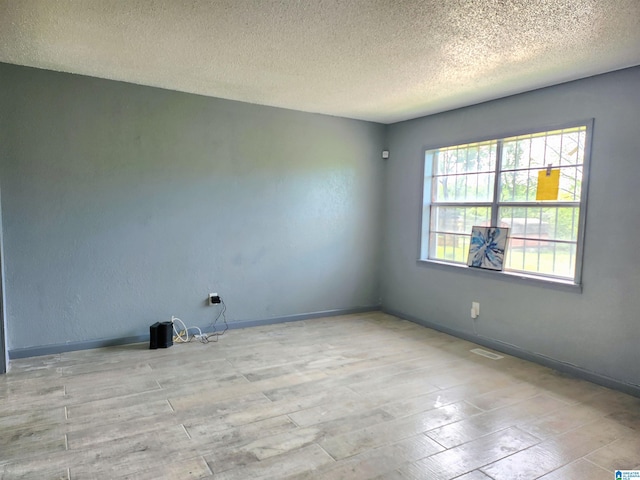 spare room featuring a textured ceiling and light hardwood / wood-style floors