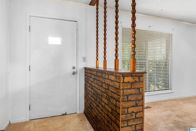 entryway with carpet and crown molding