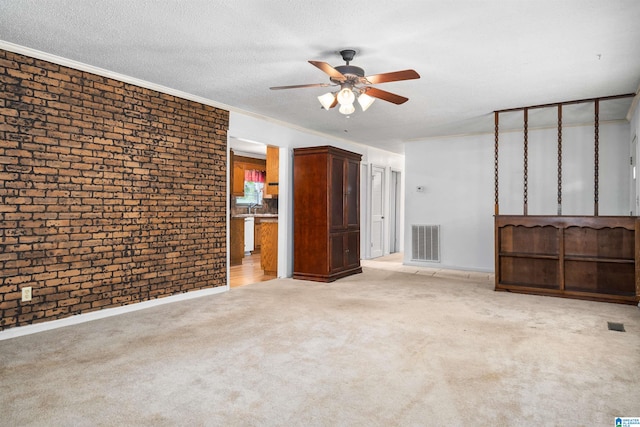 carpeted spare room featuring ceiling fan, a textured ceiling, sink, brick wall, and crown molding