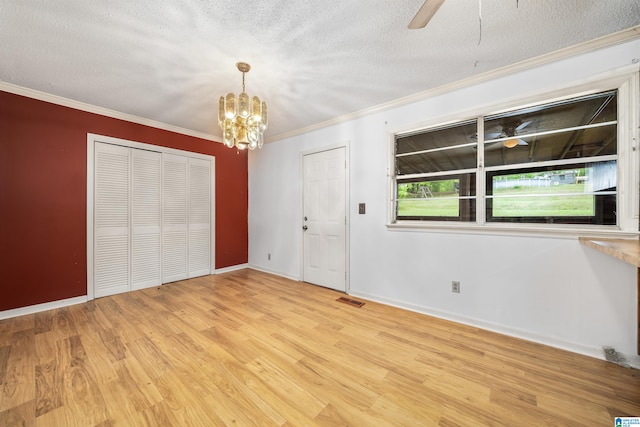 interior space featuring ceiling fan with notable chandelier, a textured ceiling, light wood-type flooring, and ornamental molding