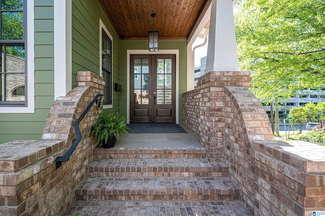 view of exterior entry featuring french doors and a porch