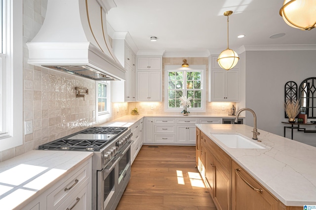 kitchen with light hardwood / wood-style floors, custom range hood, double oven range, sink, and tasteful backsplash