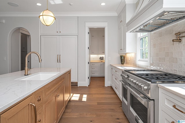 kitchen with decorative light fixtures, range with two ovens, hardwood / wood-style flooring, tasteful backsplash, and sink