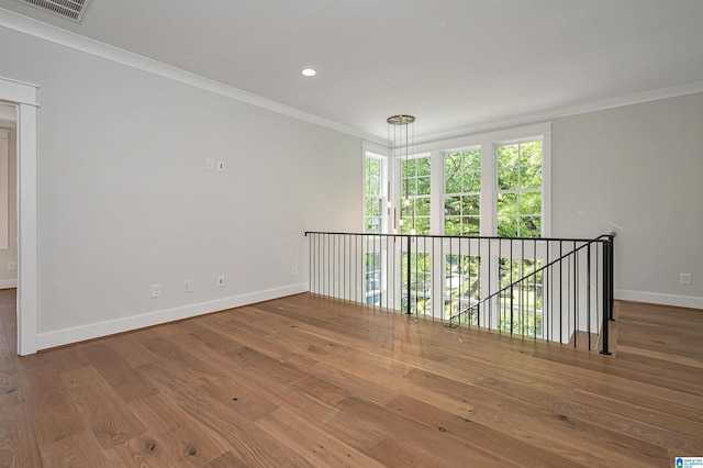 empty room with wood-type flooring and ornamental molding