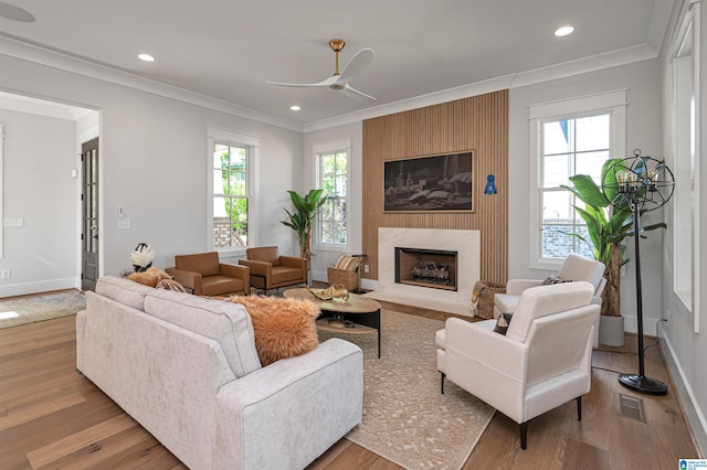 living room featuring ornamental molding, a fireplace, ceiling fan, and hardwood / wood-style floors